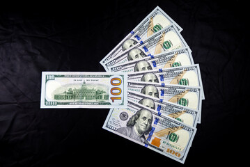 fan of 100 American dollar notes on a dark background	