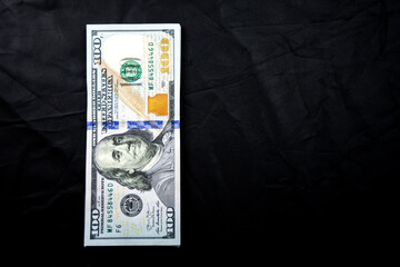 front of a 100 US dollar note on a dark background
