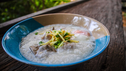 Close up Rice porridge ,congee with minced pork and ginger in white and blue bowl,Rice soup concept, on the wooden table