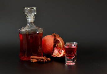 Pomegranate liqueur with cinnamon and anise, strong homemade alcohol in a bottle and two glasses on...