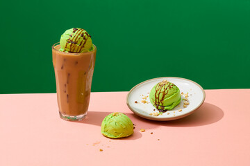 Front view of matcha ice cream balls adorned with chocolate sauce and crushed nuts on a dark...