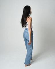 Full length portrait of brunette female model wearing casual clothes, white singlet shirt, denim...