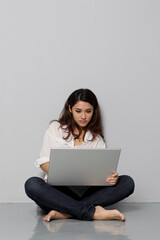 Close-up of young woman leaning on a wall and using laptop