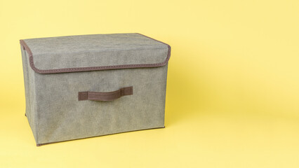 Grey cloth storage box on a yellow background.