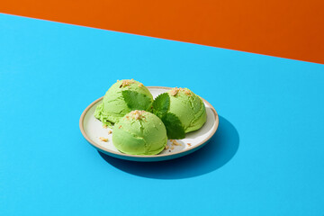 Close-up of three matcha ice cream balls decorated with basil leaves and crushed nuts on a round...