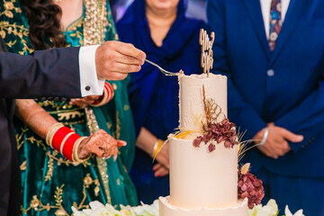 Indian couple's cutting a wedding cake close up
