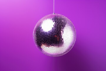 Fototapeta premium Top view of a violet background with a shiny disco ball Room for text