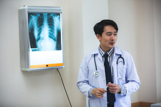 Expertise and professional Male doctor or physician show x-ray film result and explaining, analyzing and diagnosis of health problem, cancer, flu in lung or heart or bone fracture at room in hospital.