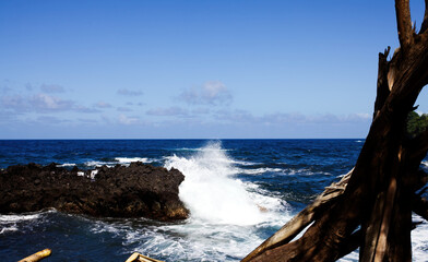 Blue Ocean And Sky With Waves Crashing On Black Lava Rock