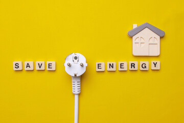 Save Energy words written on wooden cubes with electric plug and a house symbol on yellow...