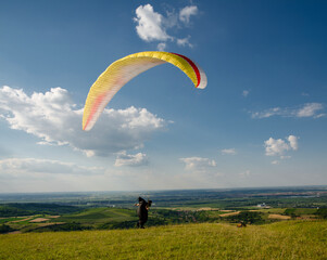 Man running high speed on field in nature ready to takeoff with paraglider 