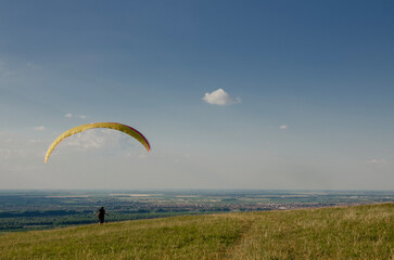 Paraglider pilot running on field, getting ready for flight