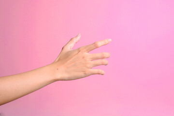 Woman's hand trying to reach or grab something isolated over pink background