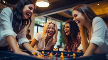 Team building, break and business women playing game in office lounge room having fun and bonding together. Trendy, cool and diversity of creative staff with fun mini table football match.