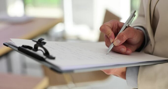 Employee with clipboard in hand writes notes on paper