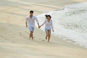 Fototapeta na wymiar Asian couple running the beach.