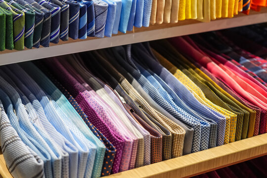 Ties of red shade and colorful tones with strict design pattern are folded in row in the window of fashionable mens clothing store.