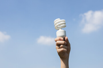 Recyclable electric waste held in hand up on sky background. Hand holding light bulb for recycle reduce and reuse concept to promote clean environment with recycling management. Gyre - obrazy, fototapety, plakaty