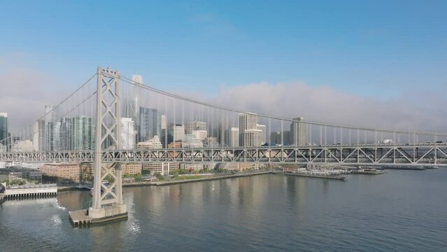 Financial district with business offices covered by morning fog at sunrise, California USA 4K. Cinematic drone flight along scenic Bay Bridge above San Francisco bay with downtown on motion background