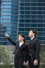 Asian business people standing in front of a skyscraper.