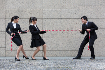 Business people having a tug of war fight.