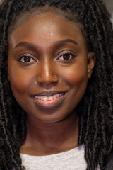 The photograph captures a young Black woman with a soft and confident smile. Her natural twist-out hairstyle perfectly frames her glowing face, highlighting her eyes that sparkle with vivacity. The