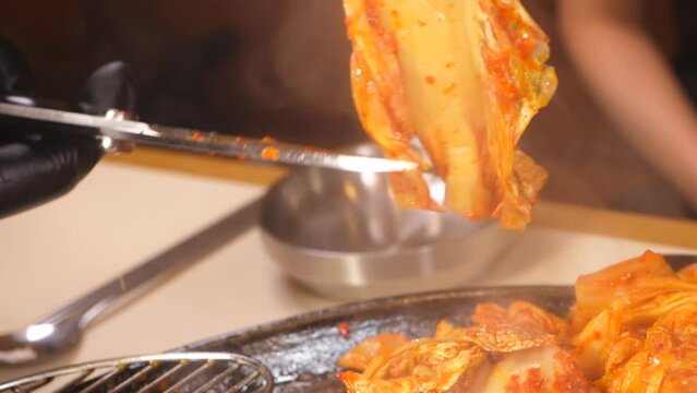 육즙 가득하게 노릇노릇 구워진 삼겹살을 상추에 올려 마늘과 구운 대파김치를 얹어 쌈을 싸먹는 모습