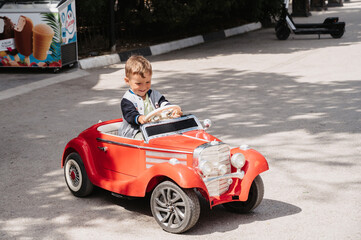 A little boy poses in a mini racing car. Play and relax in the fresh air.