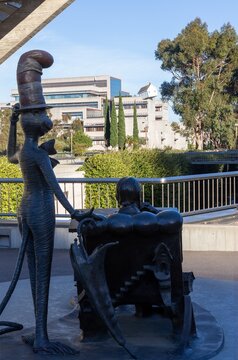 San Diego, California, USA - January 14, 2024:  Theodor Seuss, Cat in the Hat Bronze Statue Memorial, Geisel Library UCSD University Campus looking at Jacobs Engineering School Do Ho Suh Skewed House 