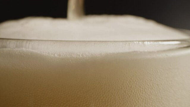 Macro closeup footage of pour the golden yellow beer bottle to glass with beer bubbles float to top