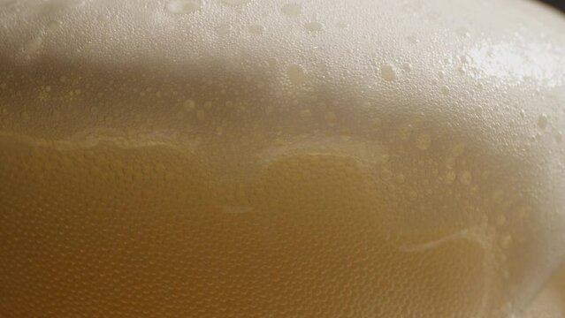Macro closeup footage of pour the golden yellow beer bottle to glass with beer bubbles float to top