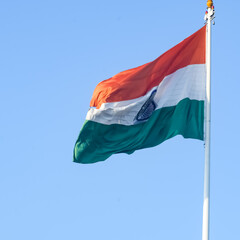 Naklejka na ściany i meble India flag flying high at Connaught Place with pride in blue sky, India flag fluttering, Indian Flag on Independence Day and Republic Day of India, tilt up shot, Waving Indian flag, Har Ghar Tiranga