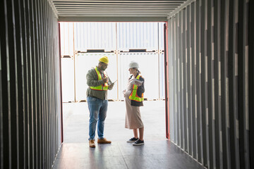 caucasian pregnancy female holds digital tablet and a fat man worker in front of opened box container,woman engineer manager inspecting the cargo,shipping company workers working at terminal port.