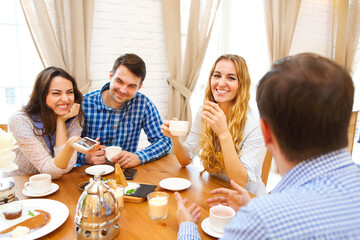 Group of four happy friends meeting and talking and eating desserts