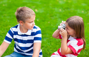 Pretty little brother and sister playing with a camera in summer park