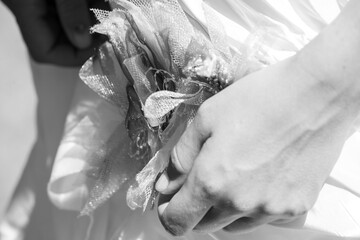 This black and white photograph captures a delicate moment between two people holding hands, with a...