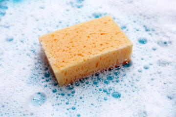 Cleaning sponge in foam of dishwashing liquid. Washing dishes concept