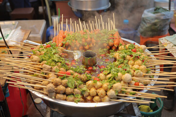 Fried meatballs on skewers soaked in dipping sauce, sold on the side of the road.