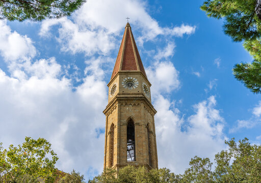 European stone clock tower of the church with a blue sky with clouds