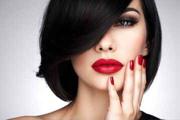 Face of a woman with beautiful dark nails and red lips. Fashion model with black shot hairs at studio