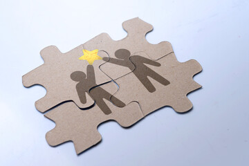 Closeup view of a jigsaw puzzle with two human figures holding a star