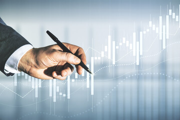 Multi exposure of trader hand with pen working with virtual abstract financial graph interface on...