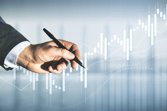Multi exposure of trader hand with pen working with virtual abstract financial graph interface on blurred office background, financial and trading concept