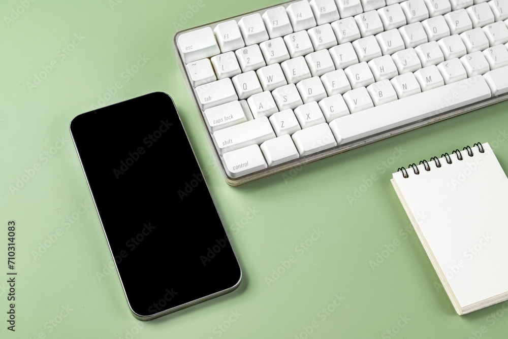 Poster closeup view of keyboard computer and mobile phone with blank screen and an empty notebook