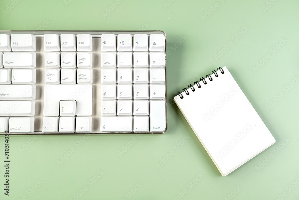 Poster closeup view of a computer keyboard with an empty notebook