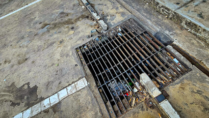 Drainage hole grating for water dirt old. Street drain is dirty and has garbage, Trash blocking...