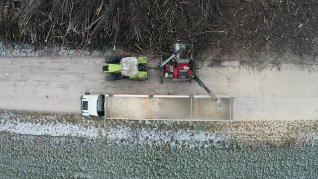 Aerial static top down view of wood chipper shred wood from pile of branches