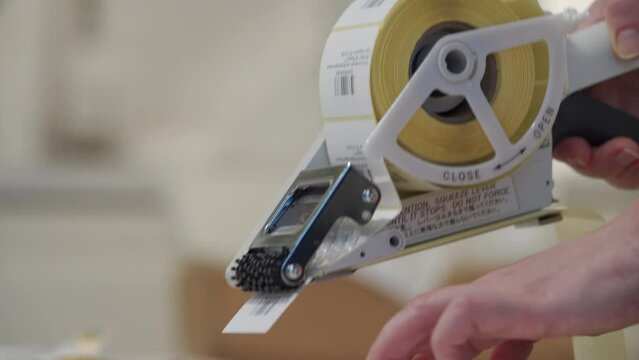 woman applying shipping barcode labels with handheld label applicator to packets