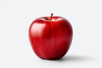 A red apple sitting on top of a white surface.