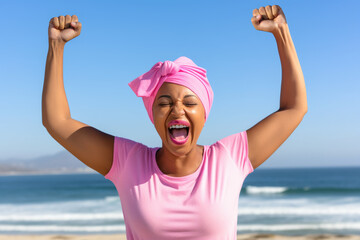 Exuberant woman with raised arms celebrating on seashore. Concept of cancer awareness. - obrazy, fototapety, plakaty